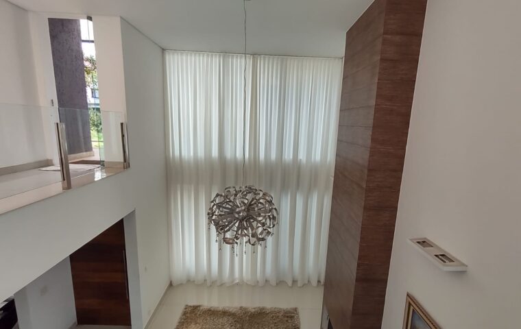 Cortina translúcida em sala com pé-direito duplo: a automação permite controlar a entrada de luz com um comando.